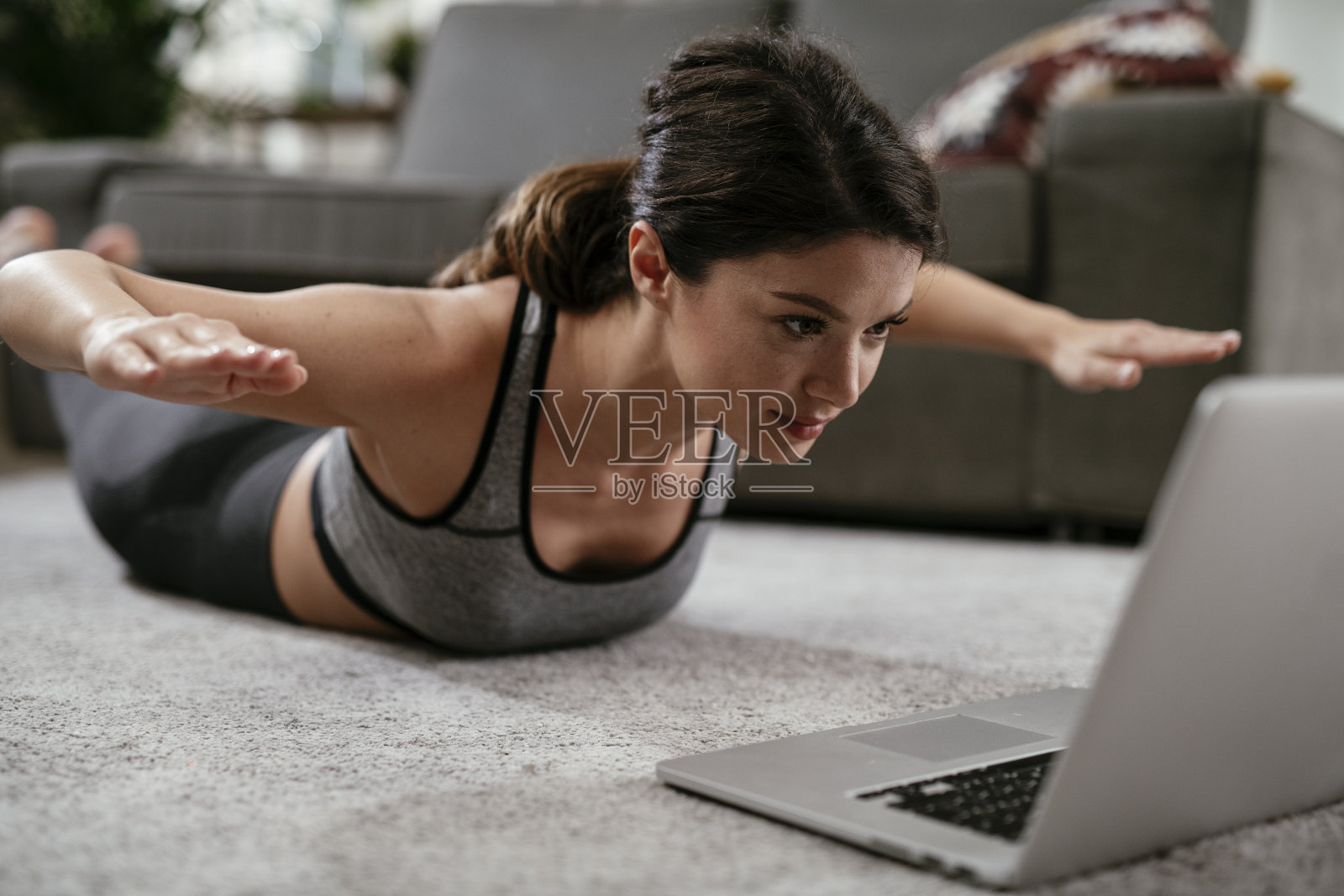 运动女性穿着运动服在家里的客厅里做伸展运动。照片摄影图片