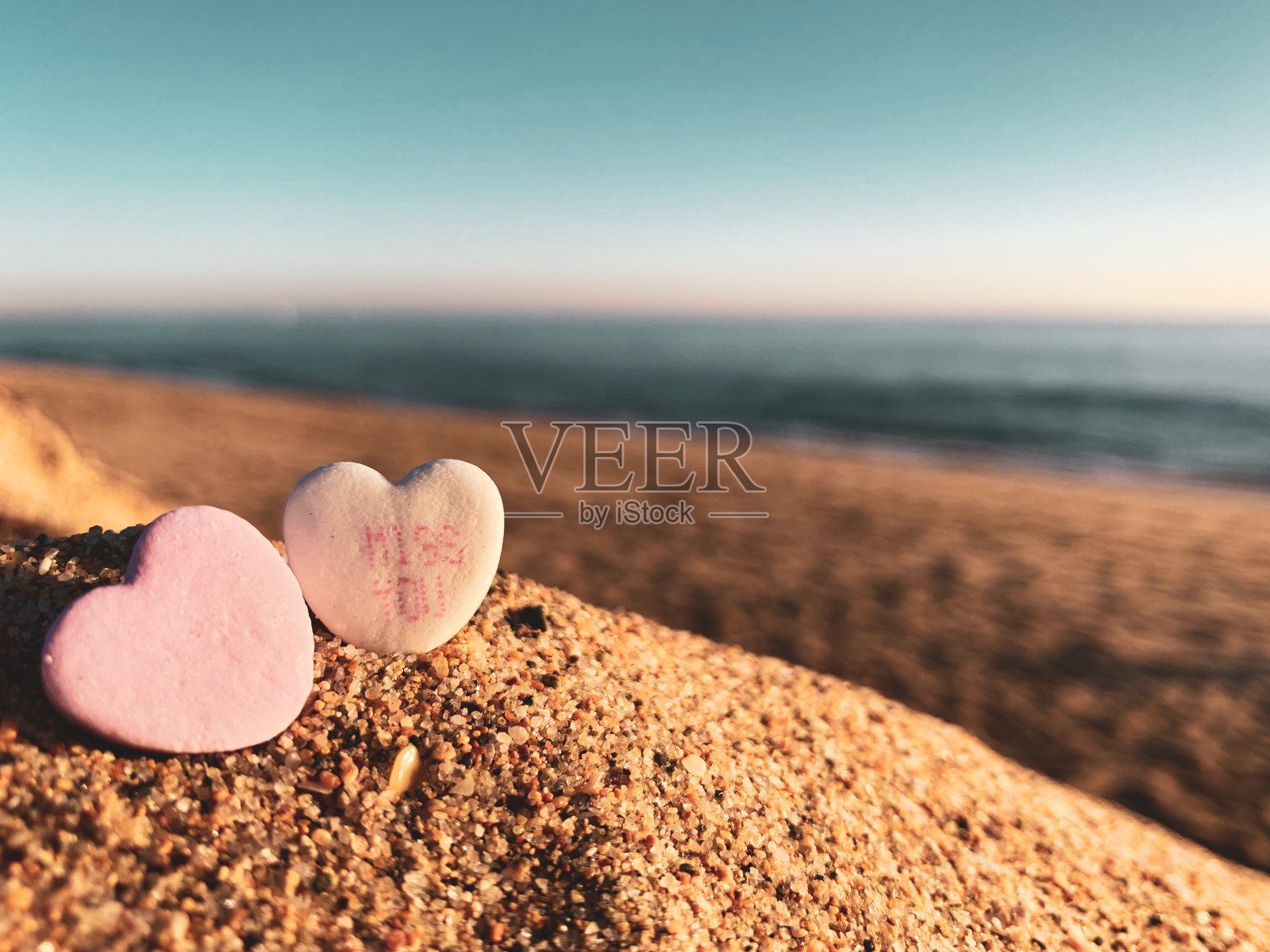 海滩上的两个心形糖果照片摄影图片