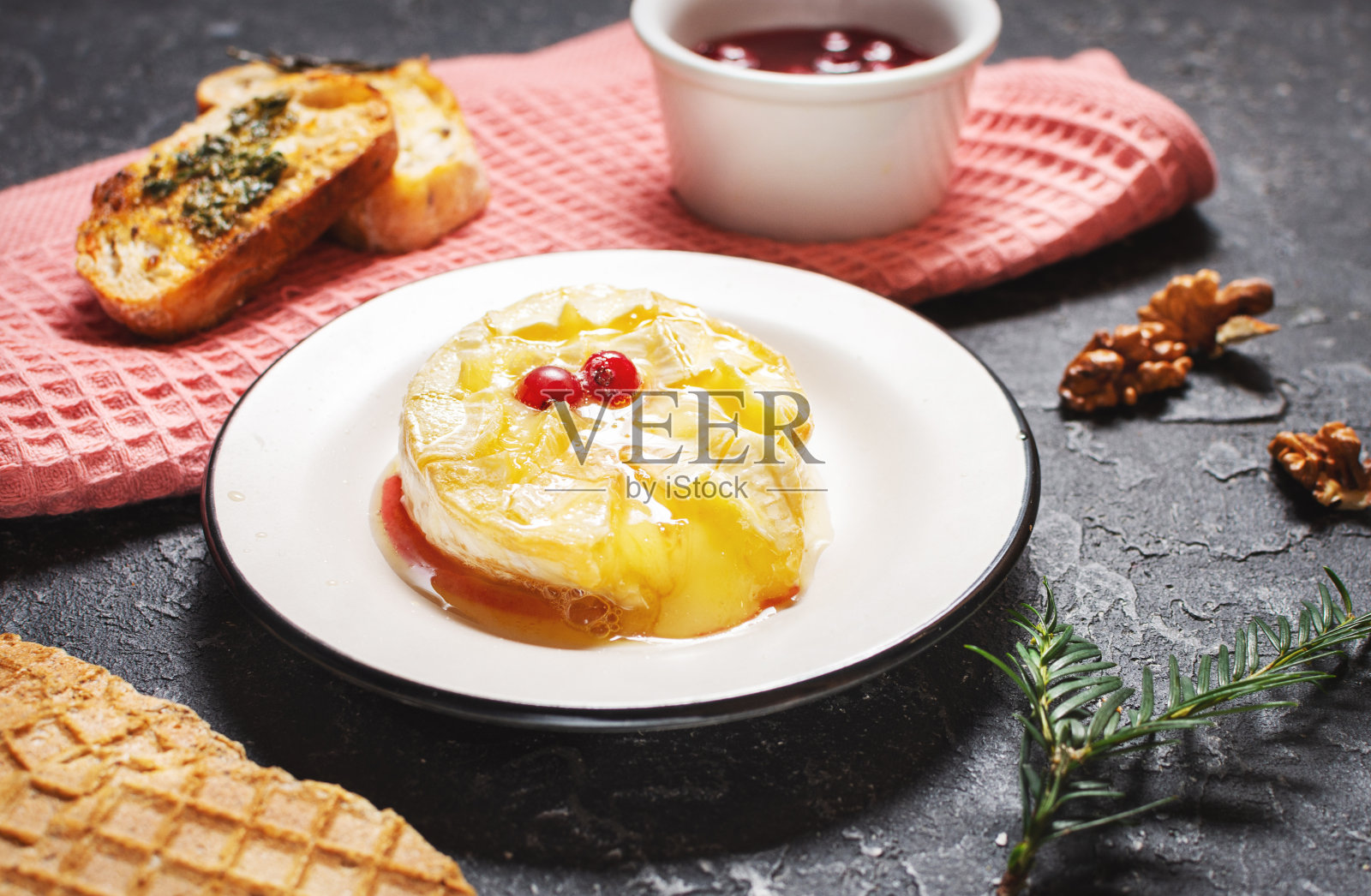 美味的烤卡门贝尔奶酪配蜂蜜，核桃，香草和蔓越莓。照片摄影图片