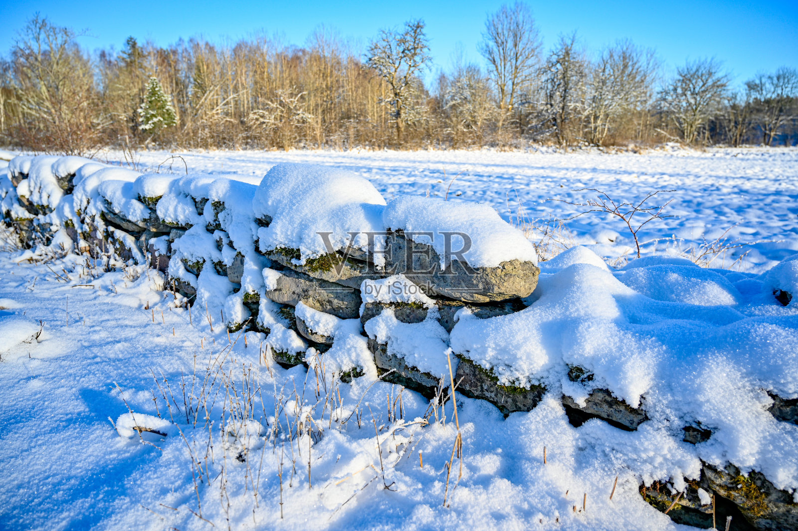 被雪覆盖的石墙靠近农田照片摄影图片
