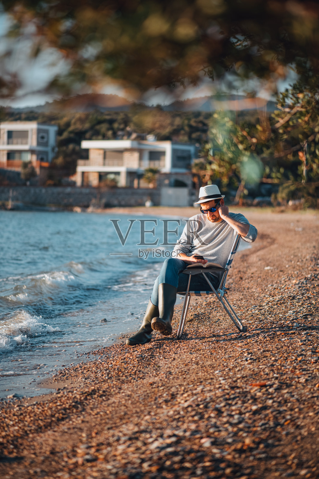 在海滩上花时间在社交媒体上的男人照片摄影图片