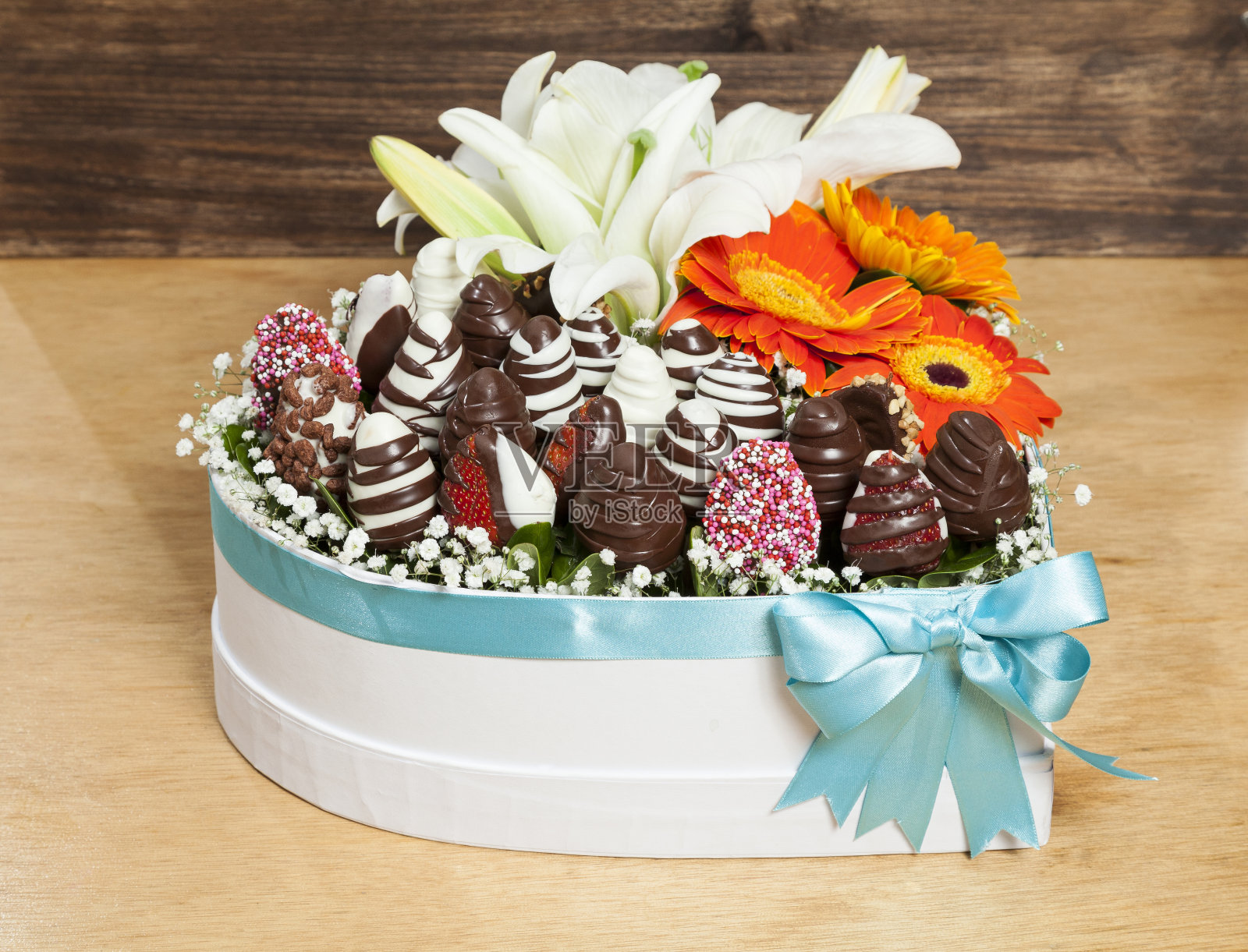 美丽的情人节礼物;一个心形的盒子，里面装满了巧克力覆盖的草莓，还有鲜花。照片摄影图片