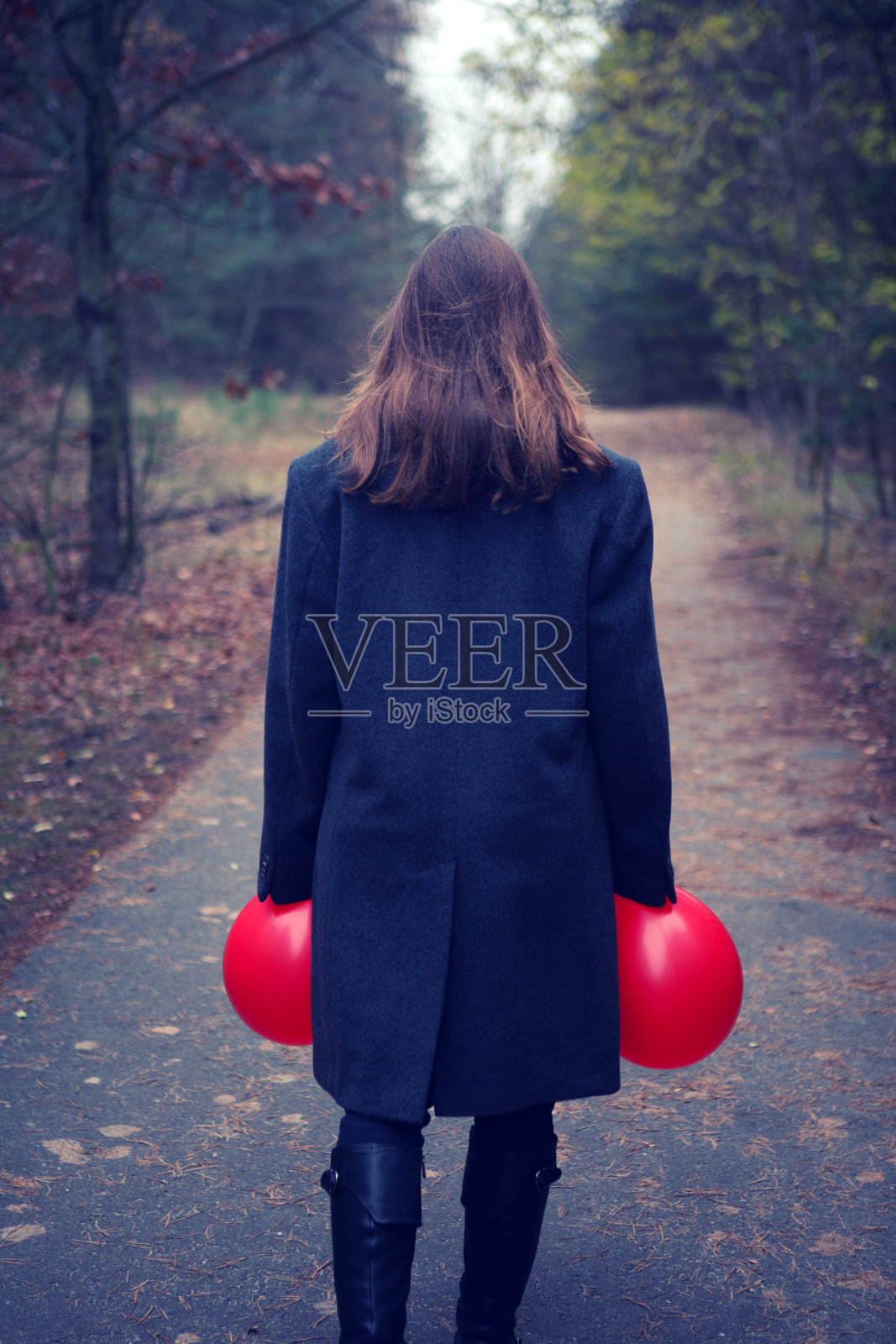 女子在森林小街上手拿两个红色气球的背影照片摄影图片