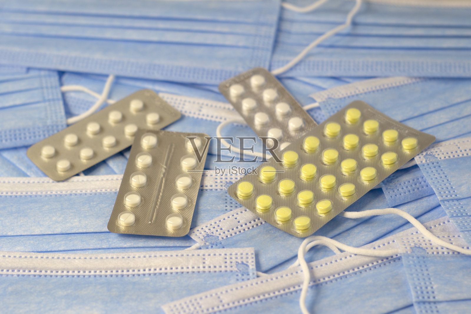 一组蓝色的面具和彩色的药丸在良好的纹理背景上聚焦线窄，景深浅照片摄影图片