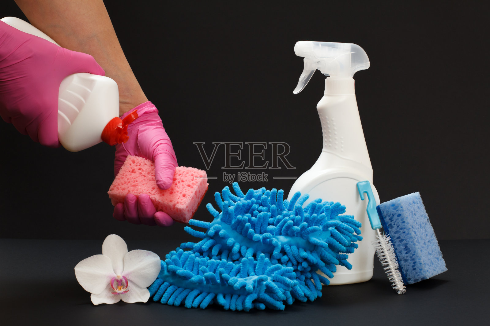 双手用海绵和一瓶洗涤液在黑色背景上。照片摄影图片