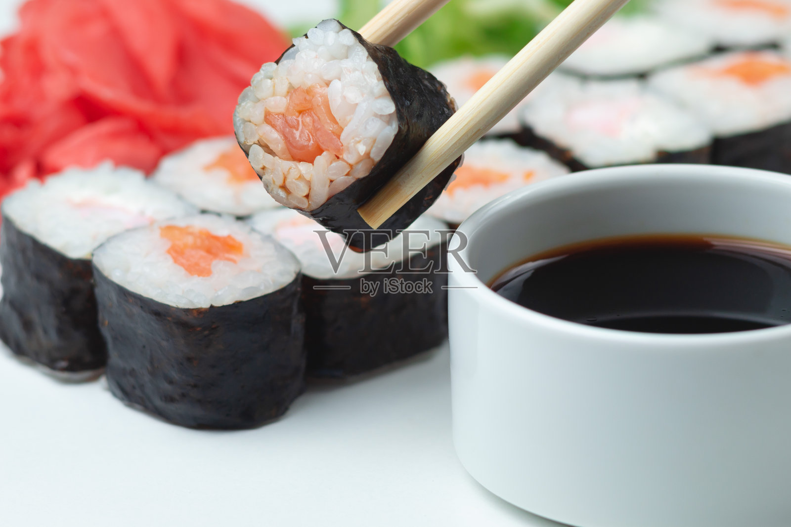 用竹竿夹着寿司卷，里面有三文鱼、米饭和酱油照片摄影图片