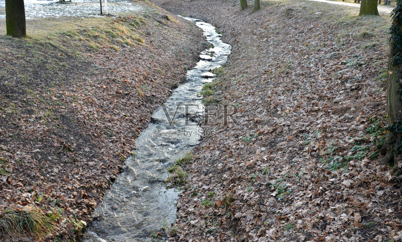洪水导致一条狭窄的河床，在那里水排得很快，弯处必须铺上一块石头，这样水的侵蚀就不会损坏弯处，水管在冬天供水照片摄影图片