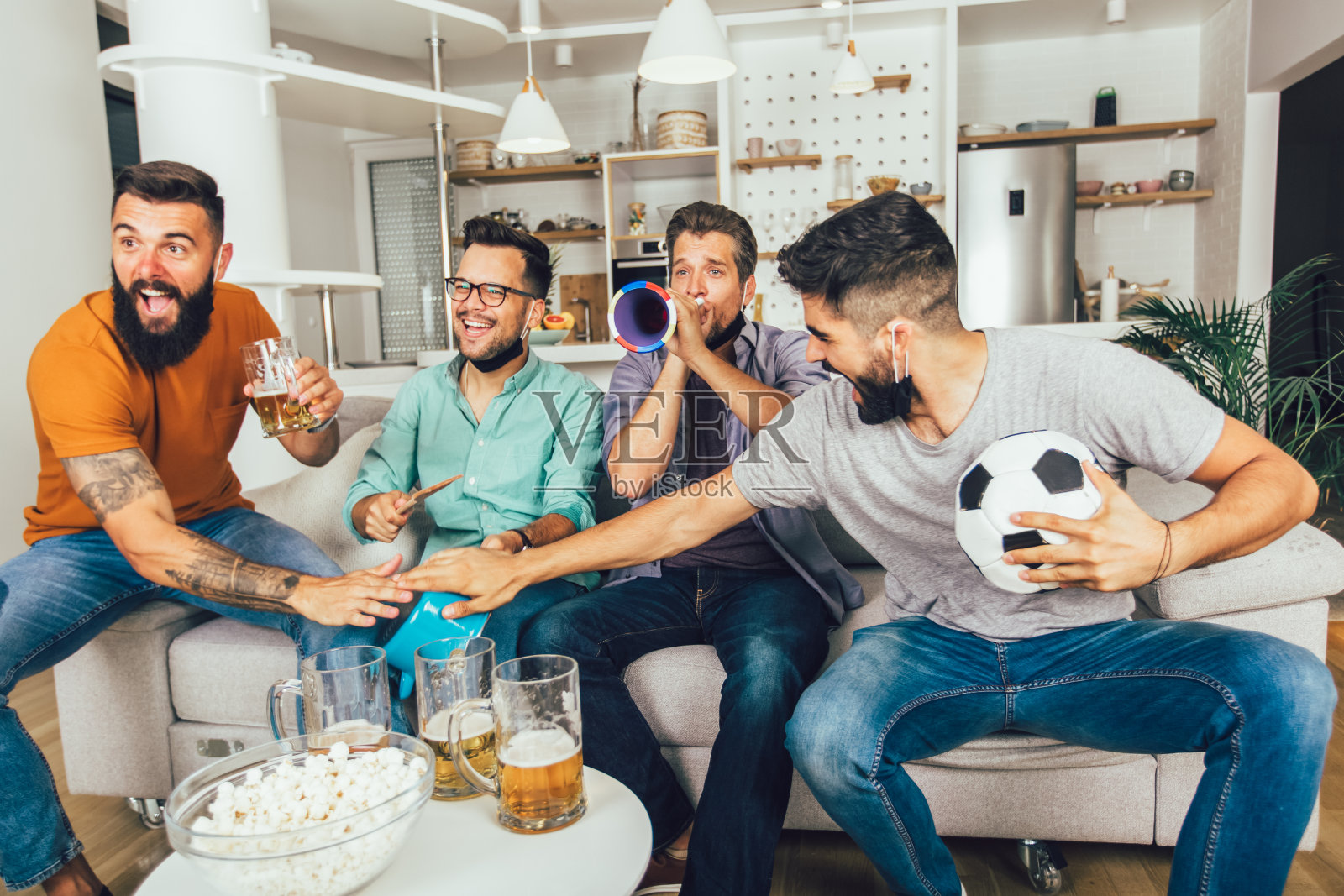 快乐的男性朋友在家看足球照片摄影图片