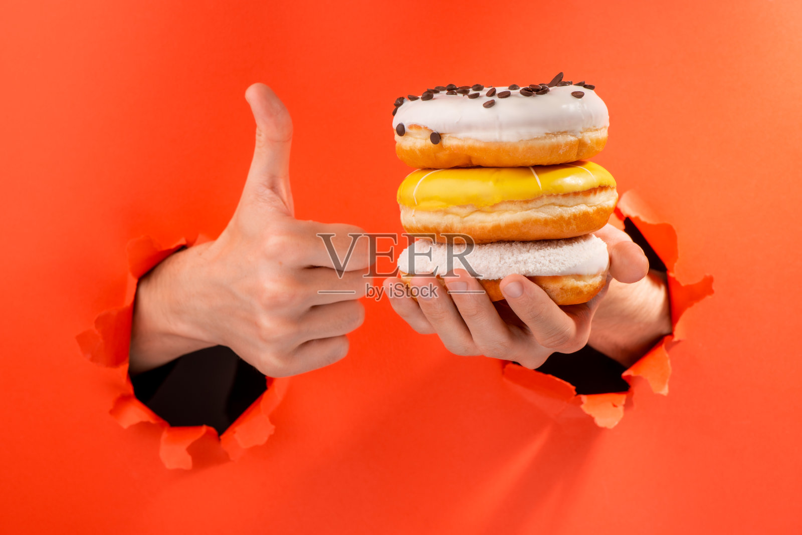 举起一堆甜甜圈，竖起大拇指照片摄影图片