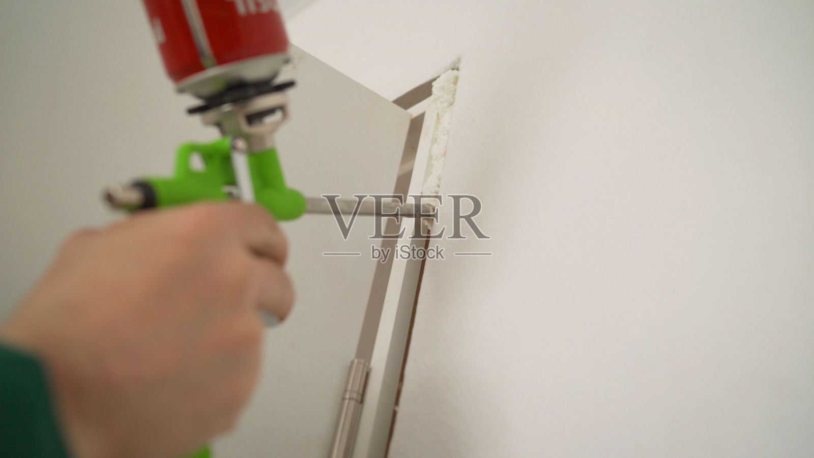 主人在安装泡沫的帮助下，修理门框。大师使用建筑泡沫。年轻人开了门。安装人员用泡沫填充门坡照片摄影图片