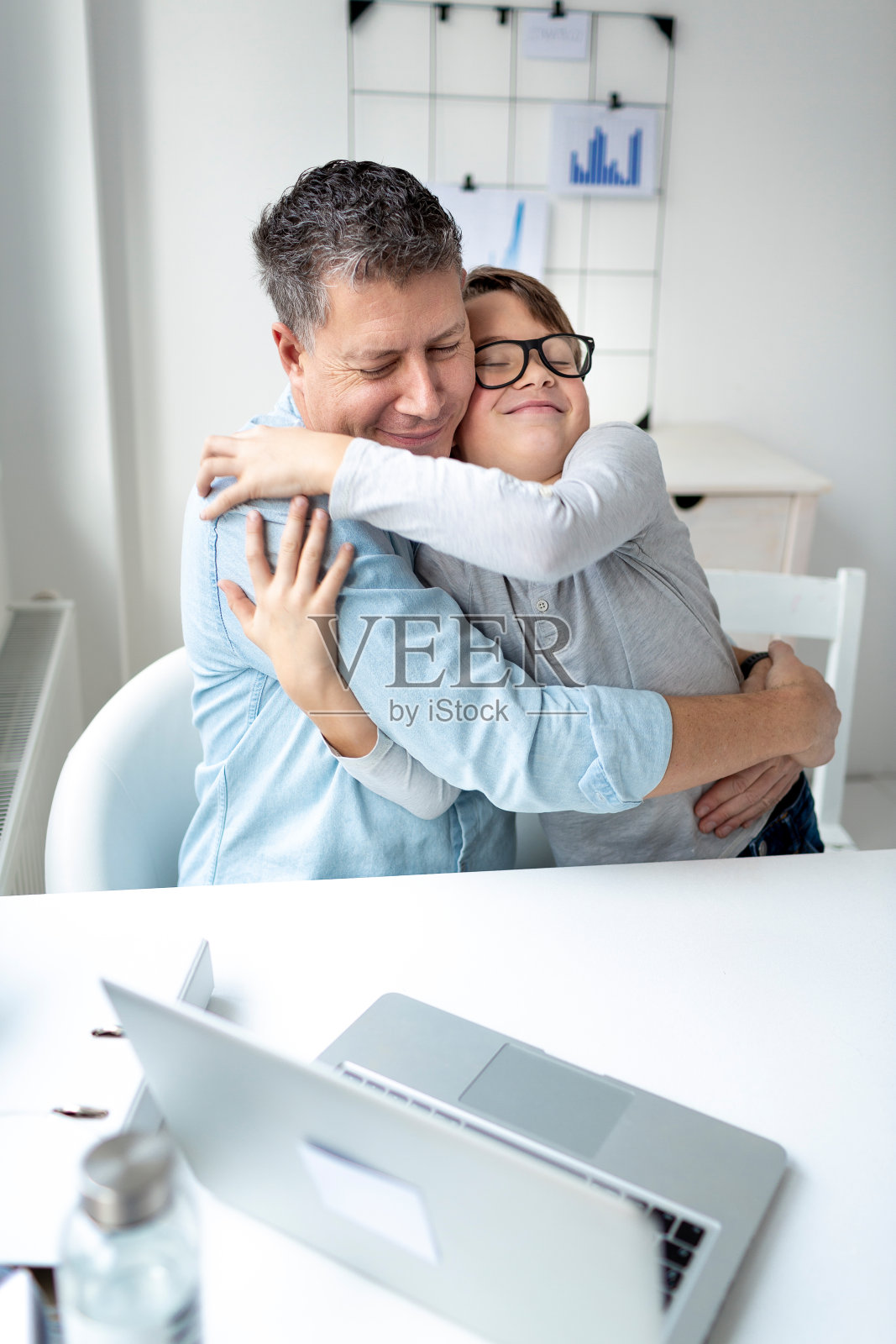 在家办公的优势。冠状病毒危机期间，父亲在家拥抱儿子照片摄影图片