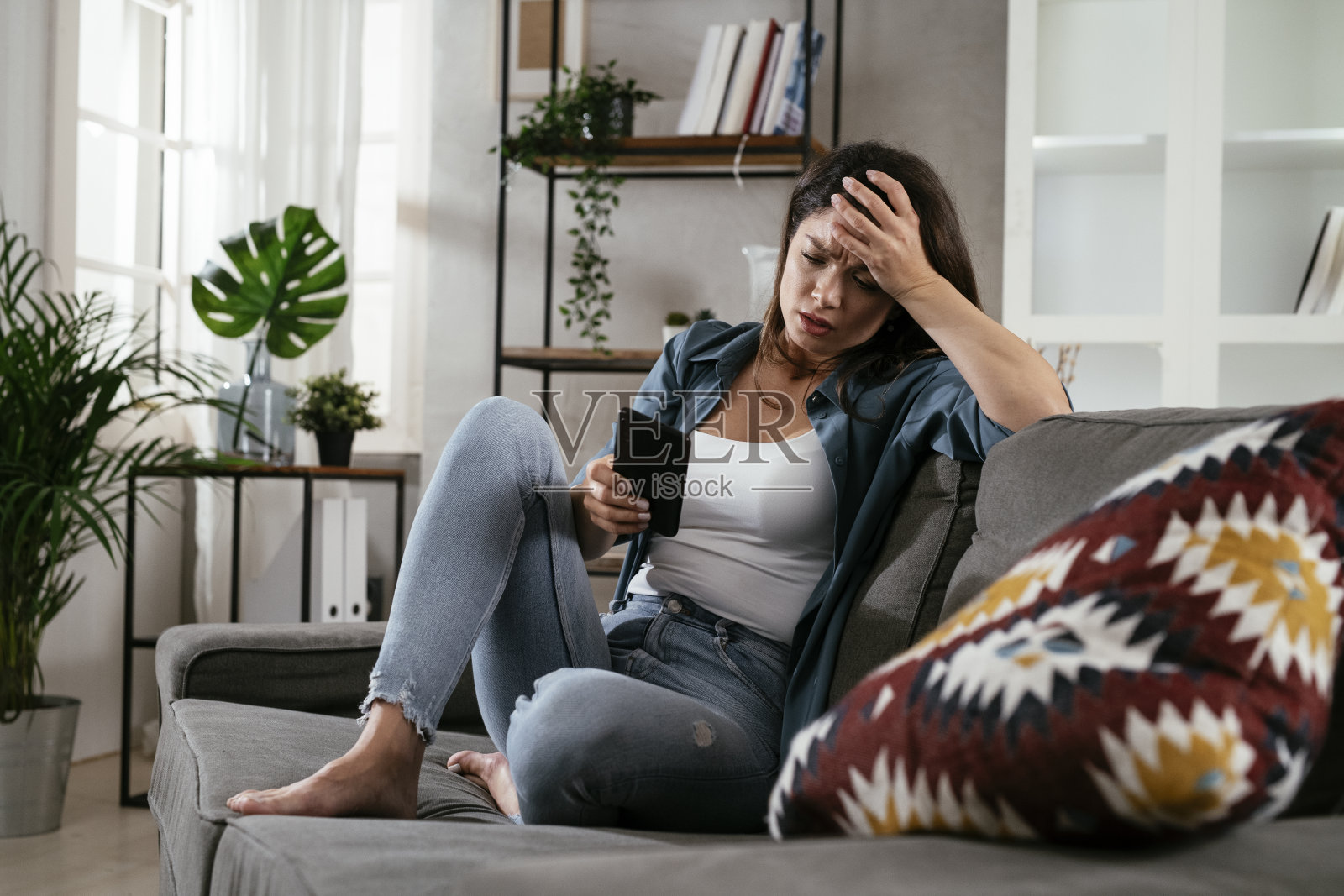 一个可悲的女人，坐在沙发上打电话照片摄影图片