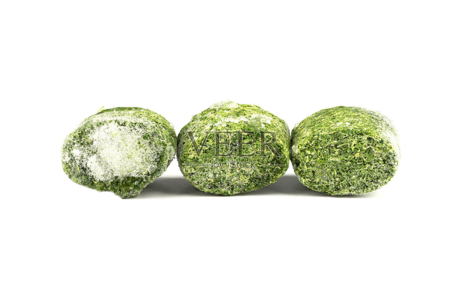在白色背景上分离的三个压成块状的冷冻菠菜叶子。照片摄影图片