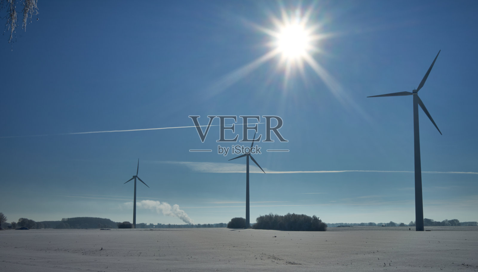 明亮的阳光在天空上方白雪覆盖的田野上用风力涡轮机产生替代能源照片摄影图片