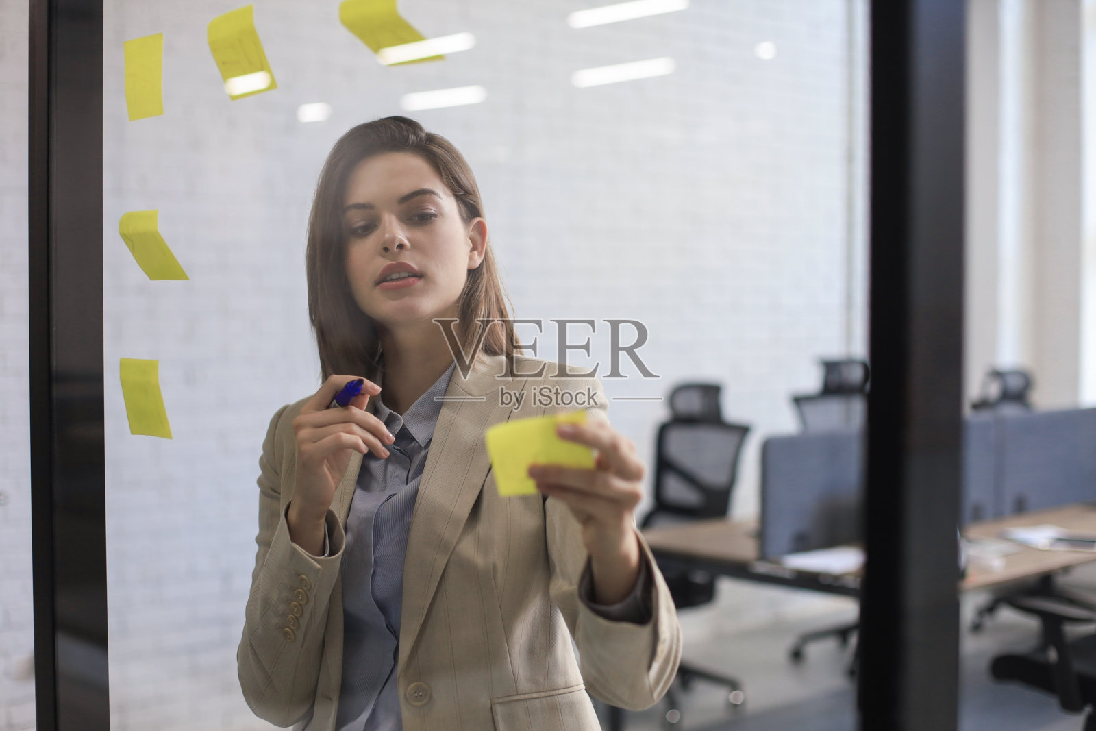 照片透过玻璃有吸引力的商业女人张贴在玻璃上的办公室和书写。照片摄影图片