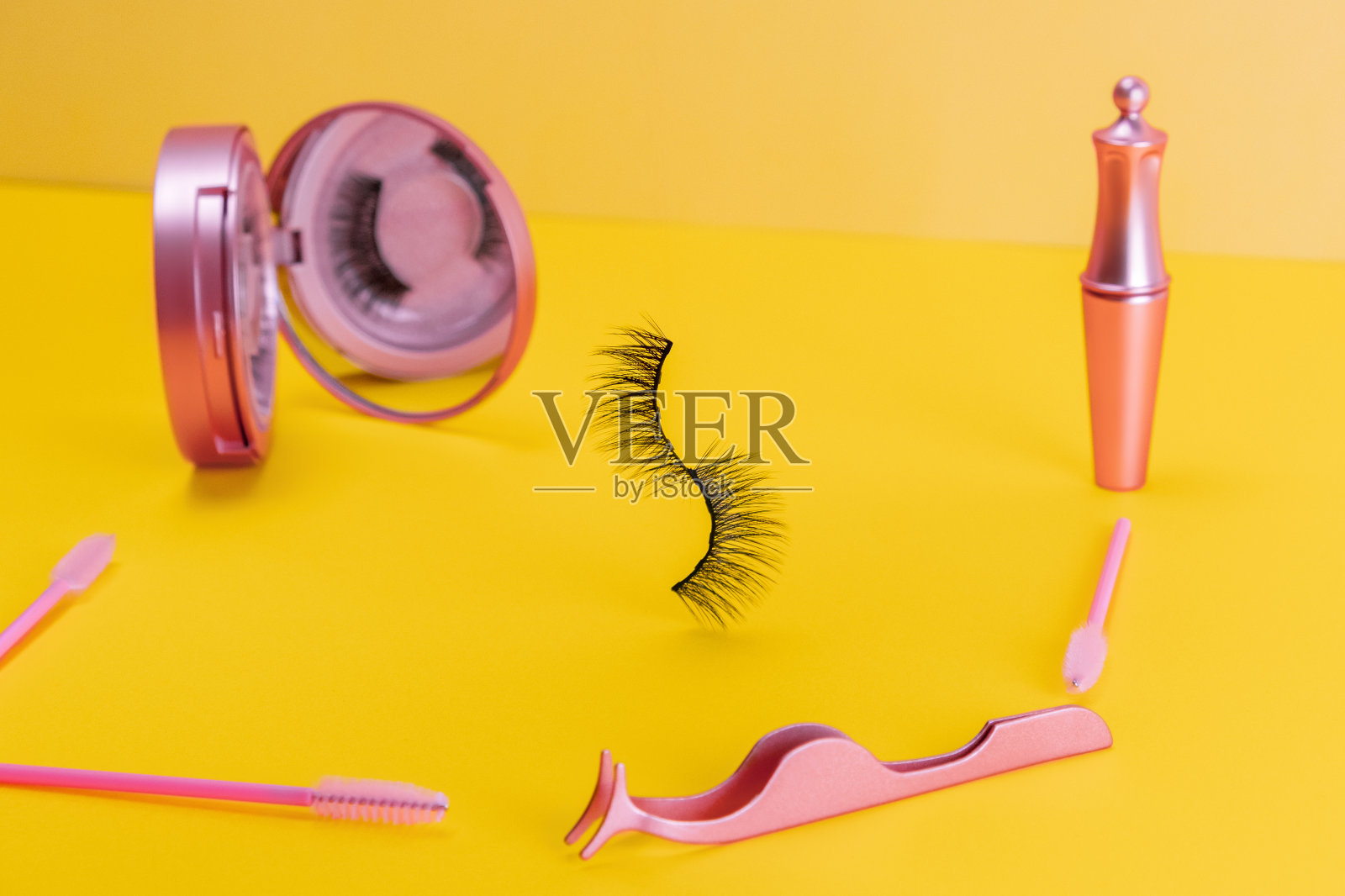 磁性假假假睫毛在粉红色镜子套件在黄色照明颜色的背景。家居睫毛延伸，美容工具概念，美容治疗。色彩趋势照片摄影图片