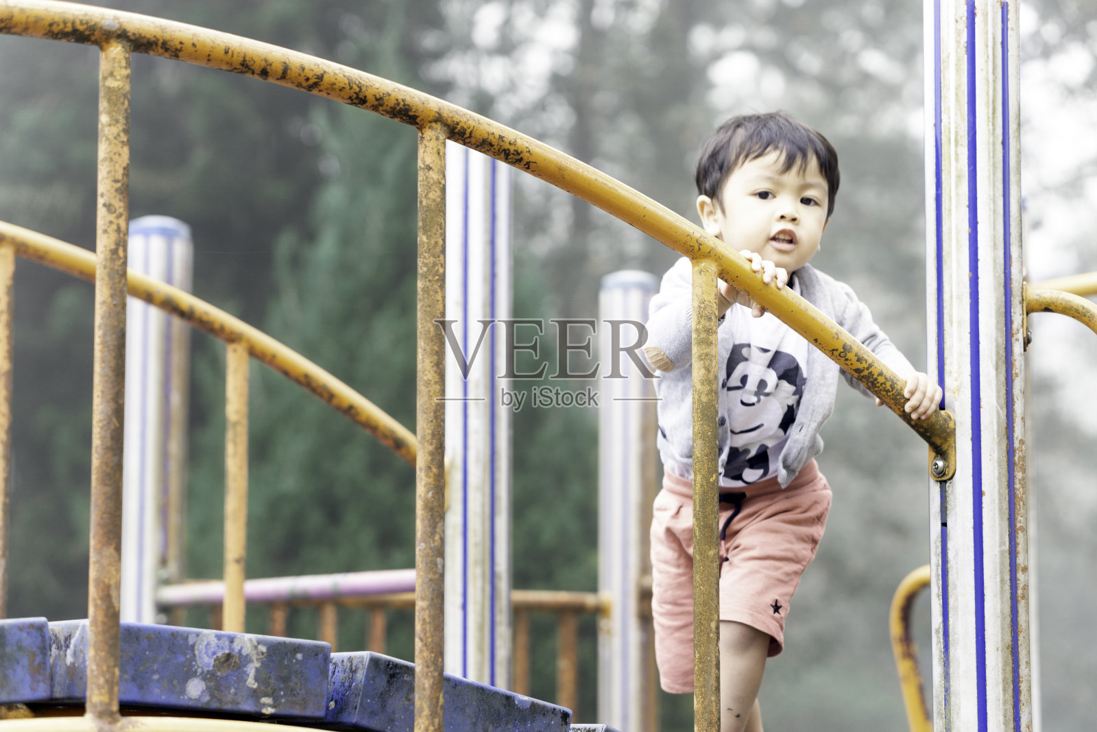 可爱的亚洲男孩在操场上玩得很开心照片摄影图片