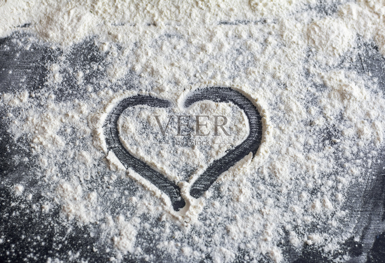 心画在撒在黑暗桌子上的面粉上。照片摄影图片