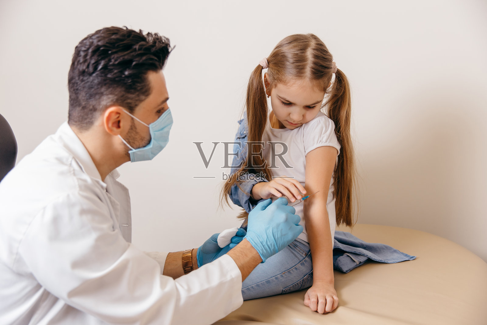 一位阿拉伯或土耳其籍医生给小女孩接种了冠状病毒疫苗。女孩们受伤了。照片摄影图片