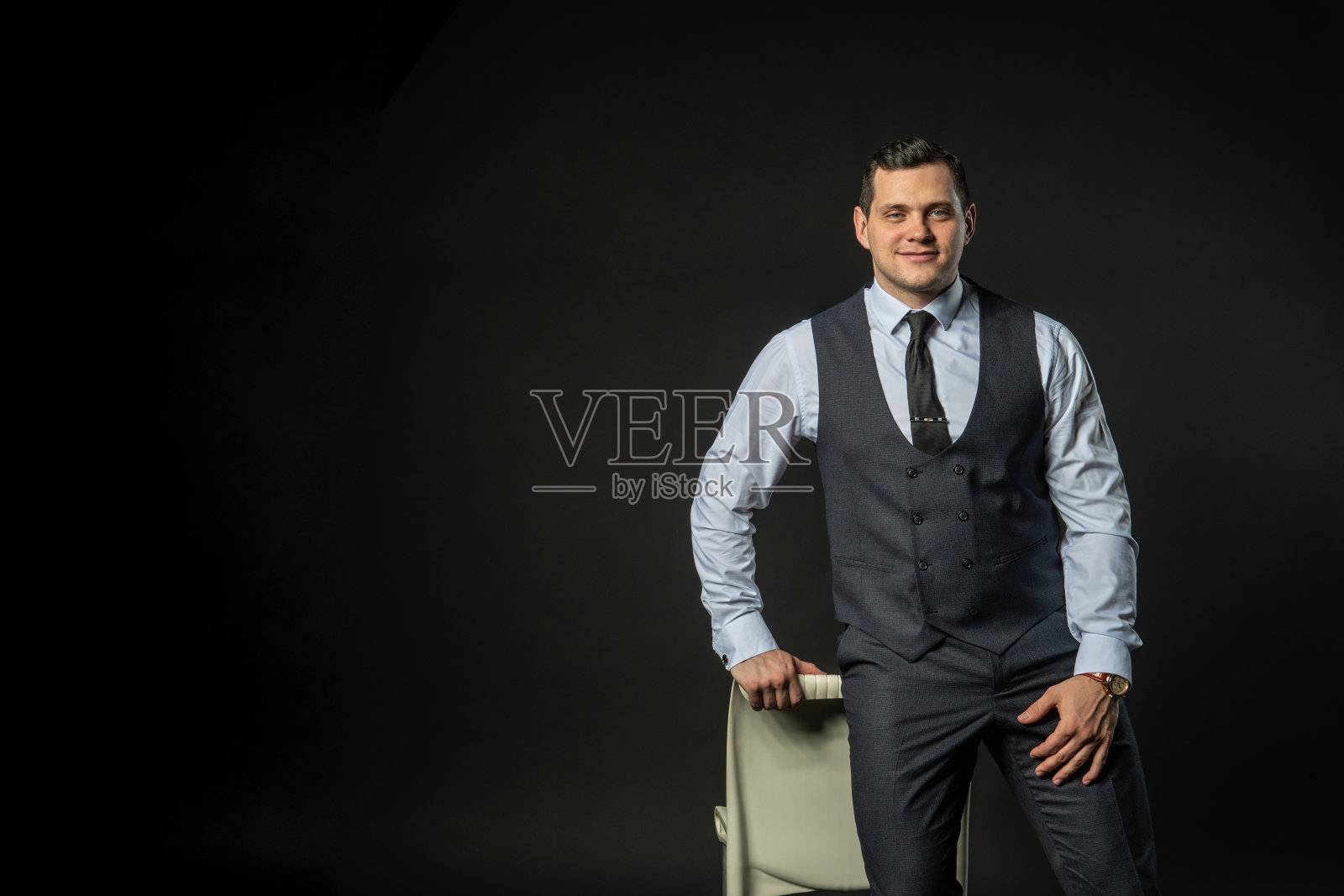 穿着三件套西装坐在椅子上年轻的男性三件套西装商业模式年轻的白人严肃正式，成功寂寞背景的黑人健美运动员照片摄影图片