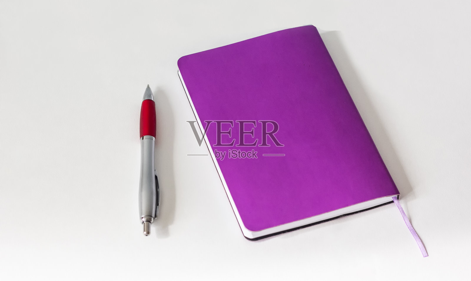 红色记事本旁边的一支笔。孤立在白色照片摄影图片
