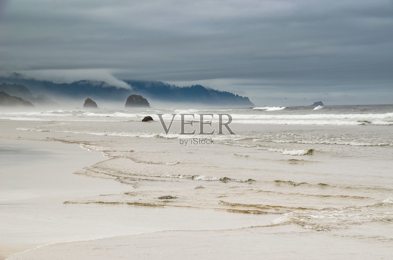 在俄勒冈州坎农海滩的暴风雨天气中，太平洋海岸线的岩石形成照片摄影图片