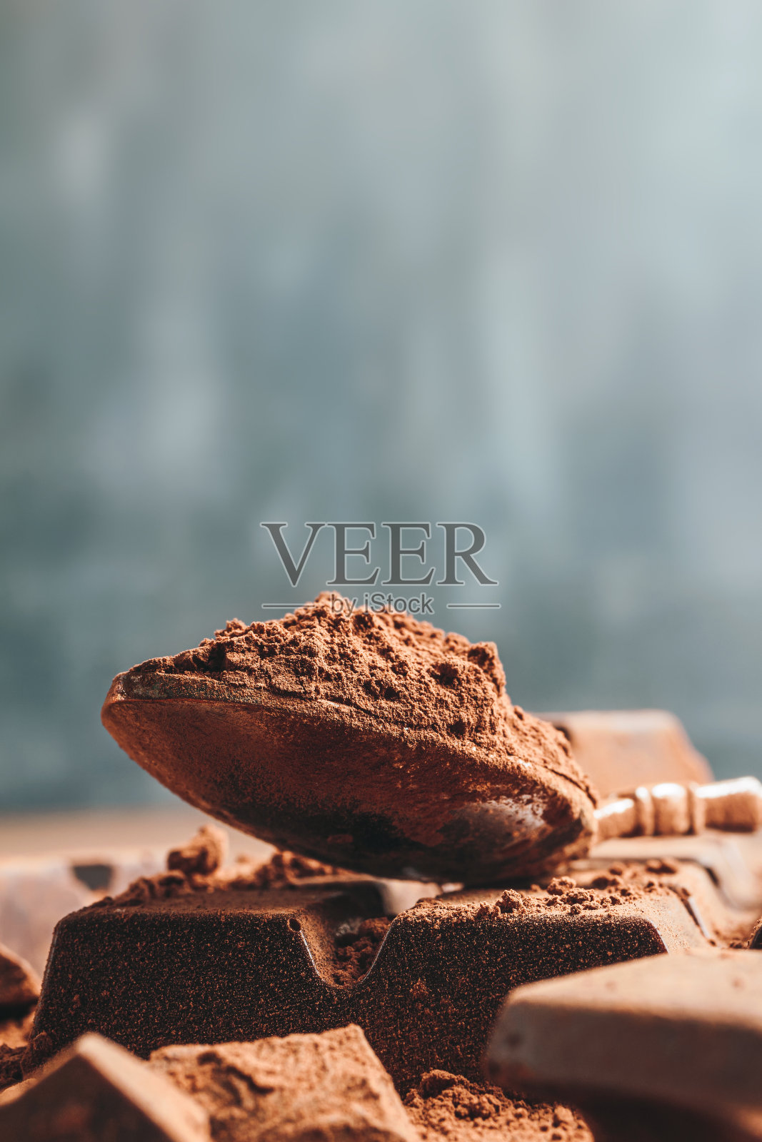 在勺子里放入棕色的可可粉和切碎的巧克力块，在深色的背景上有拷贝空间照片摄影图片