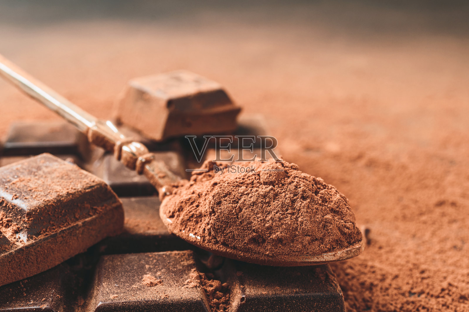 在勺子里放入棕色的可可粉和切碎的巧克力块，在深色的背景上有拷贝空间照片摄影图片