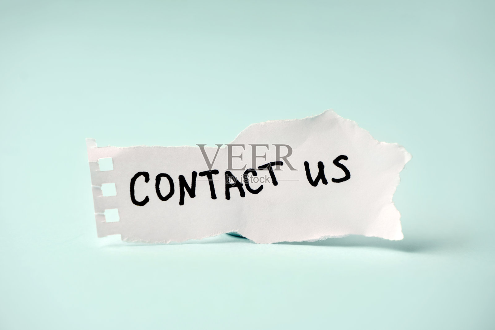 在一张蓝色背景的白纸上刻有“联系我们”字样。照片摄影图片
