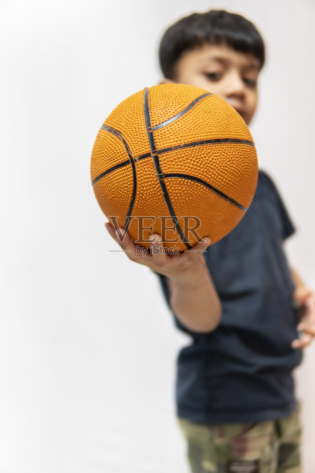 可爱的3岁小男孩拿着一个篮球。照片摄影图片