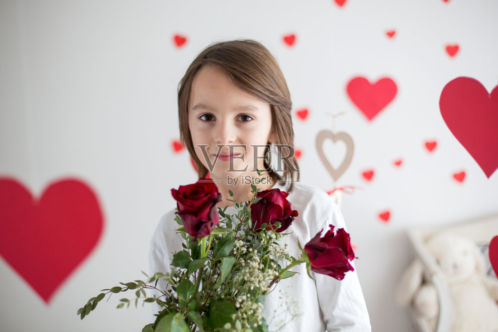 可爱的长头发学生，拿着心形盒子和红玫瑰，为情人节玩心形游戏照片摄影图片