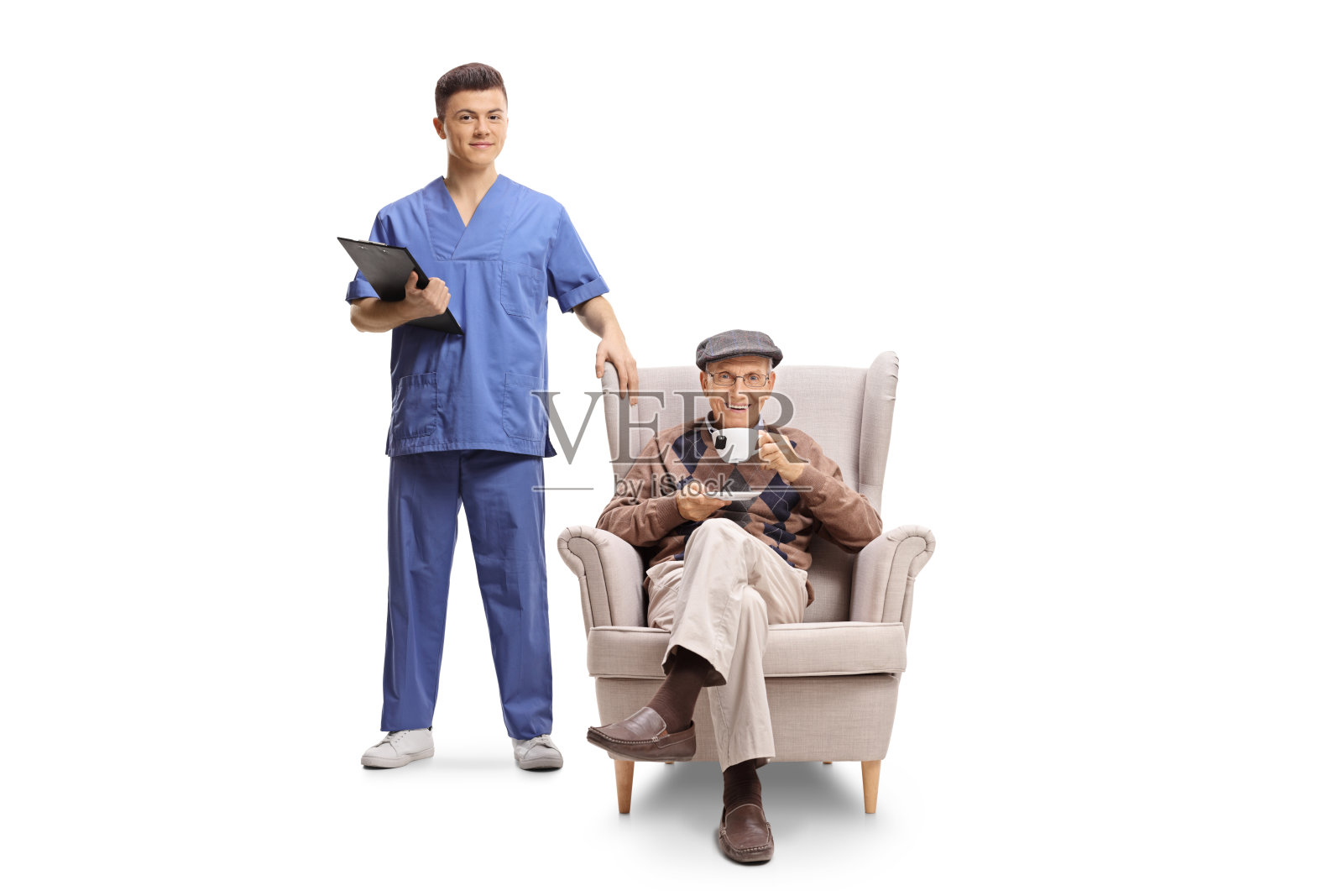 年轻男性卫生工作者拿着一个剪贴板站在一个坐在扶手椅上喝着茶的老人旁边照片摄影图片