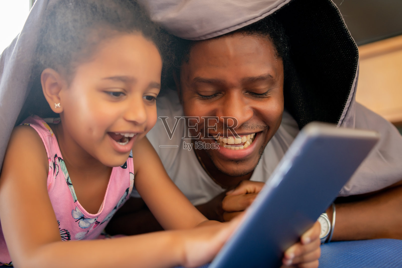 父亲和女儿在家里使用数码平板电脑。照片摄影图片