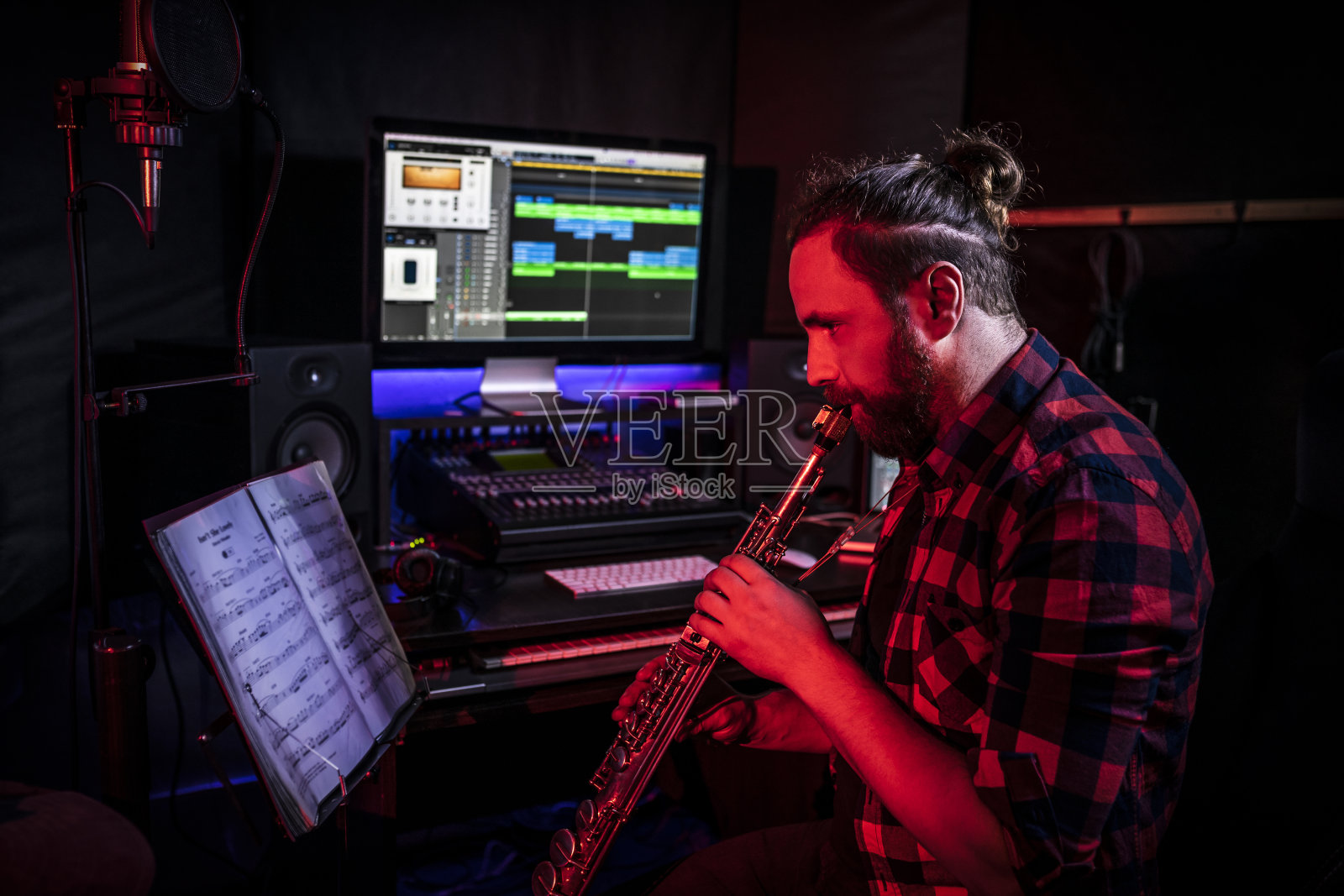 这个年轻人正在录音室里演奏乐器，录制他的新歌照片摄影图片