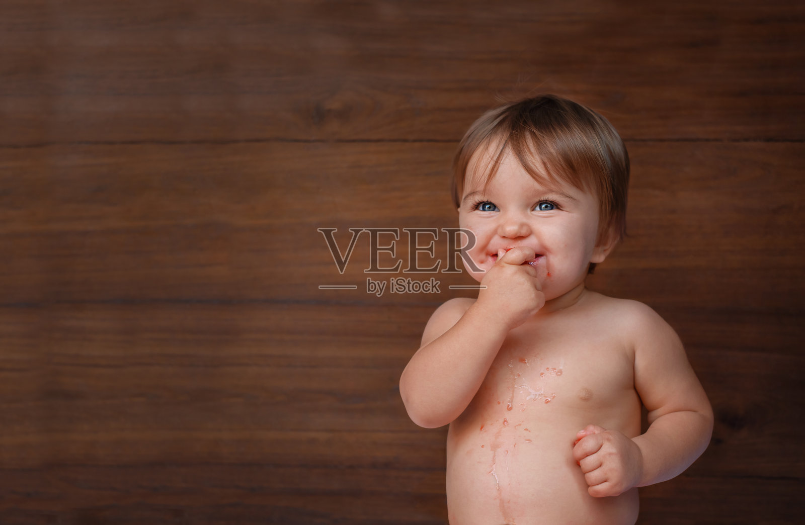 婴儿在木制背景上吃浆果。照片摄影图片