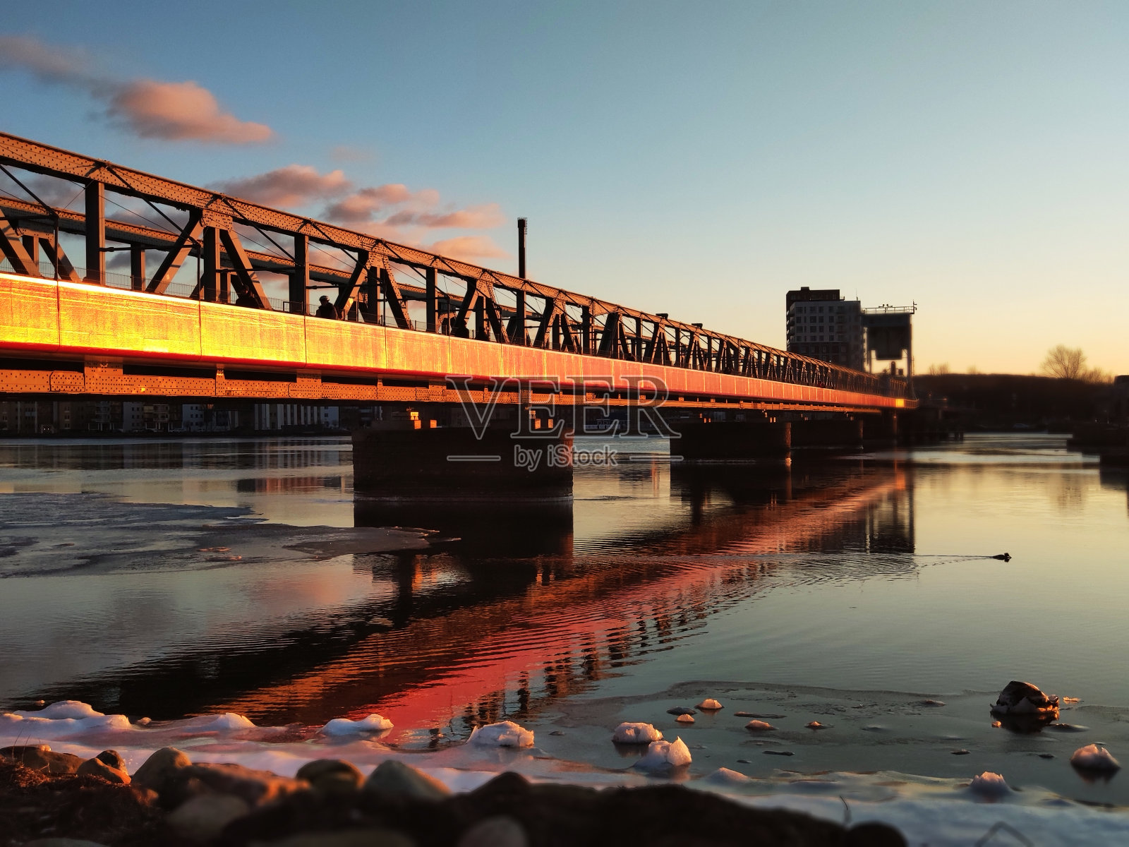 丹麦日落时冰冻的水面上的红色人行天桥照片摄影图片