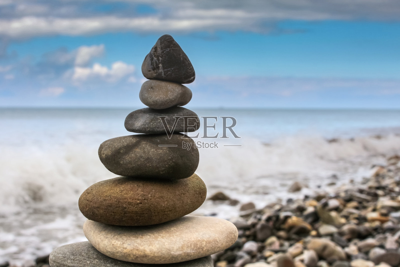 和谐塔由沙滩上的小石子组成，映衬着蔚蓝的天空照片摄影图片