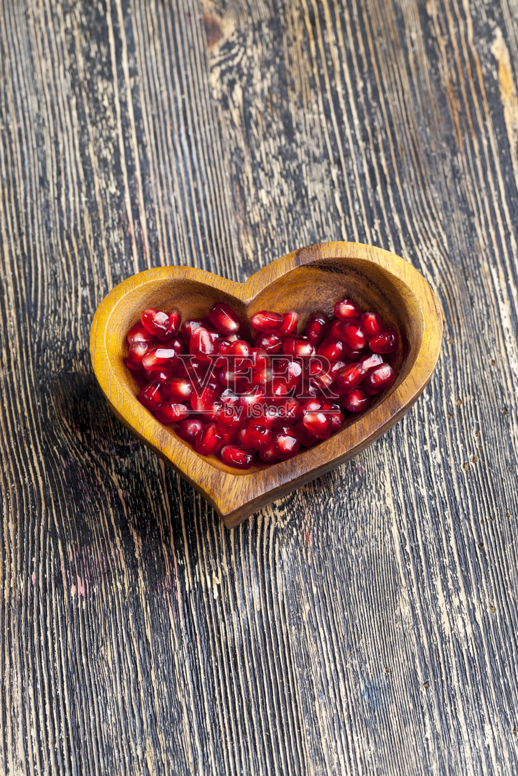 新鲜的石榴籽放在一个心形的碗里照片摄影图片