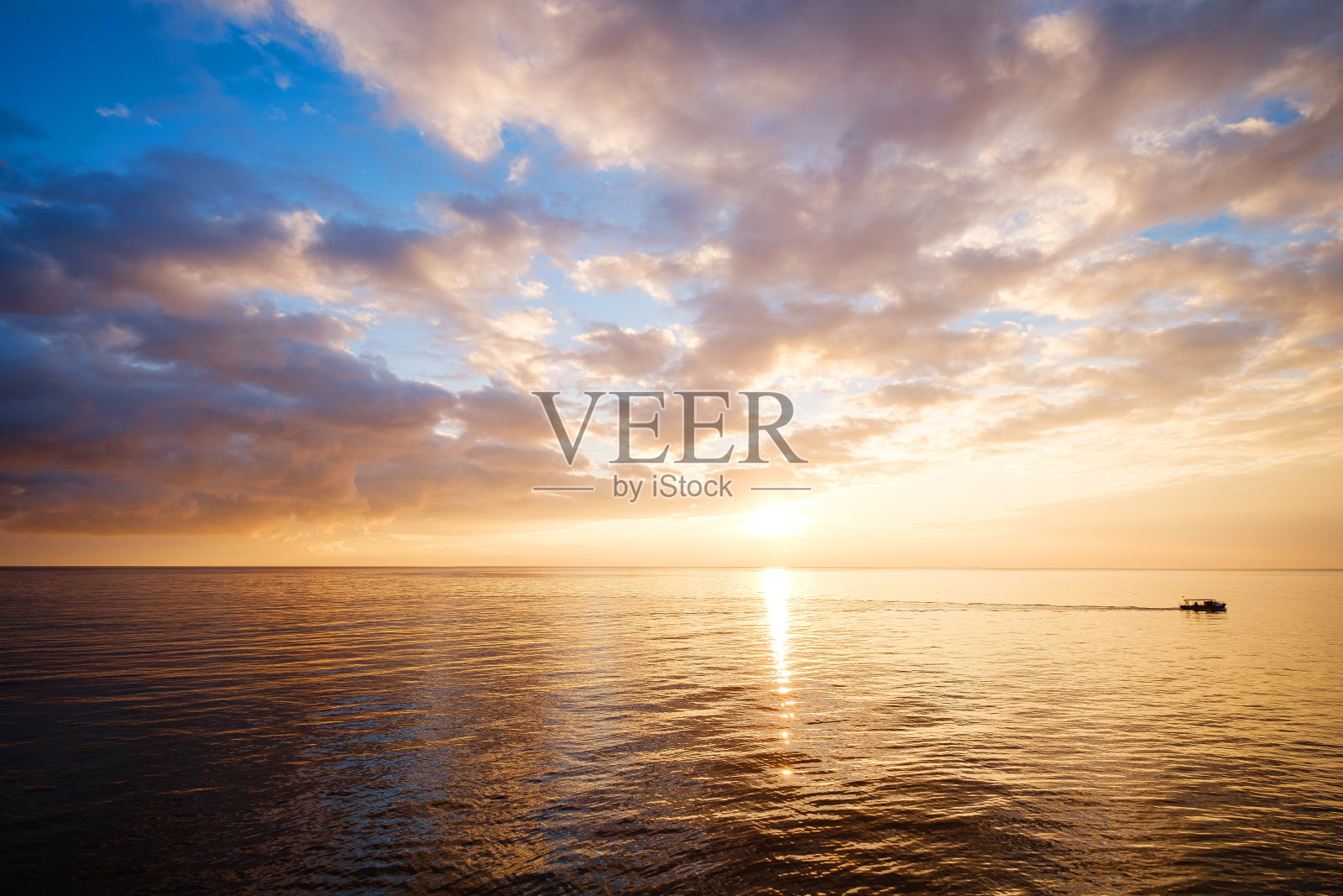 平静的海面与日落的天空和太阳透过云。照片摄影图片