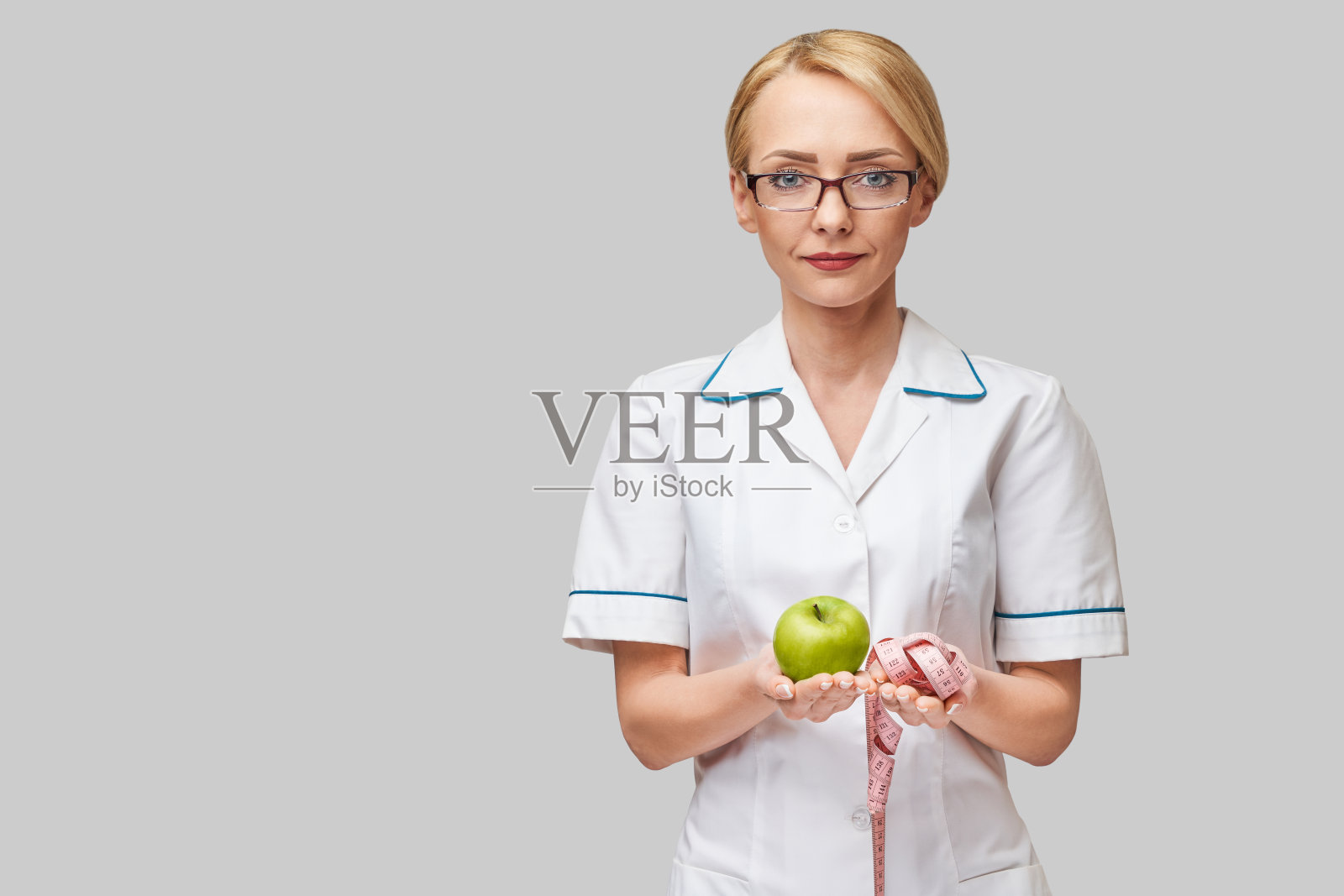 营养学家医生健康生活理念-拿着有机新鲜青苹果和测量尺照片摄影图片