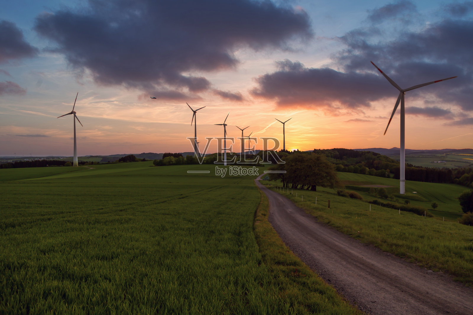 日落时，风力涡轮机在田野上照片摄影图片