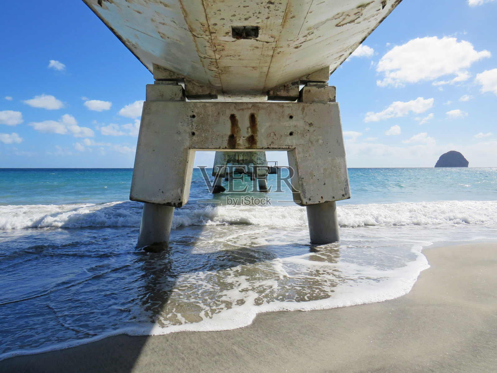 在法国西印度群岛的青绿色海洋和热带蓝色天空的桥梁底部的透视视图。加勒比海的混凝土结构。工程和建筑模式。照片摄影图片