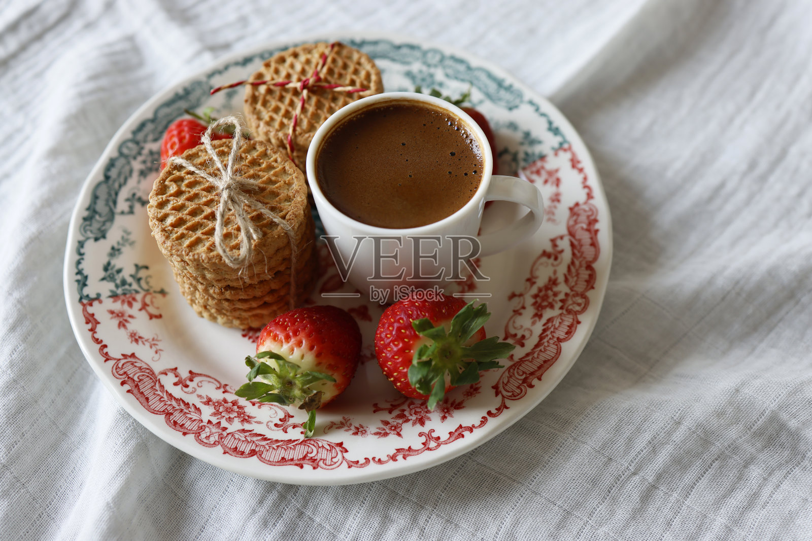 线结燕麦饼干，草莓和一杯土耳其咖啡在红绿图案的盘子，在白色的布餐巾上照片摄影图片