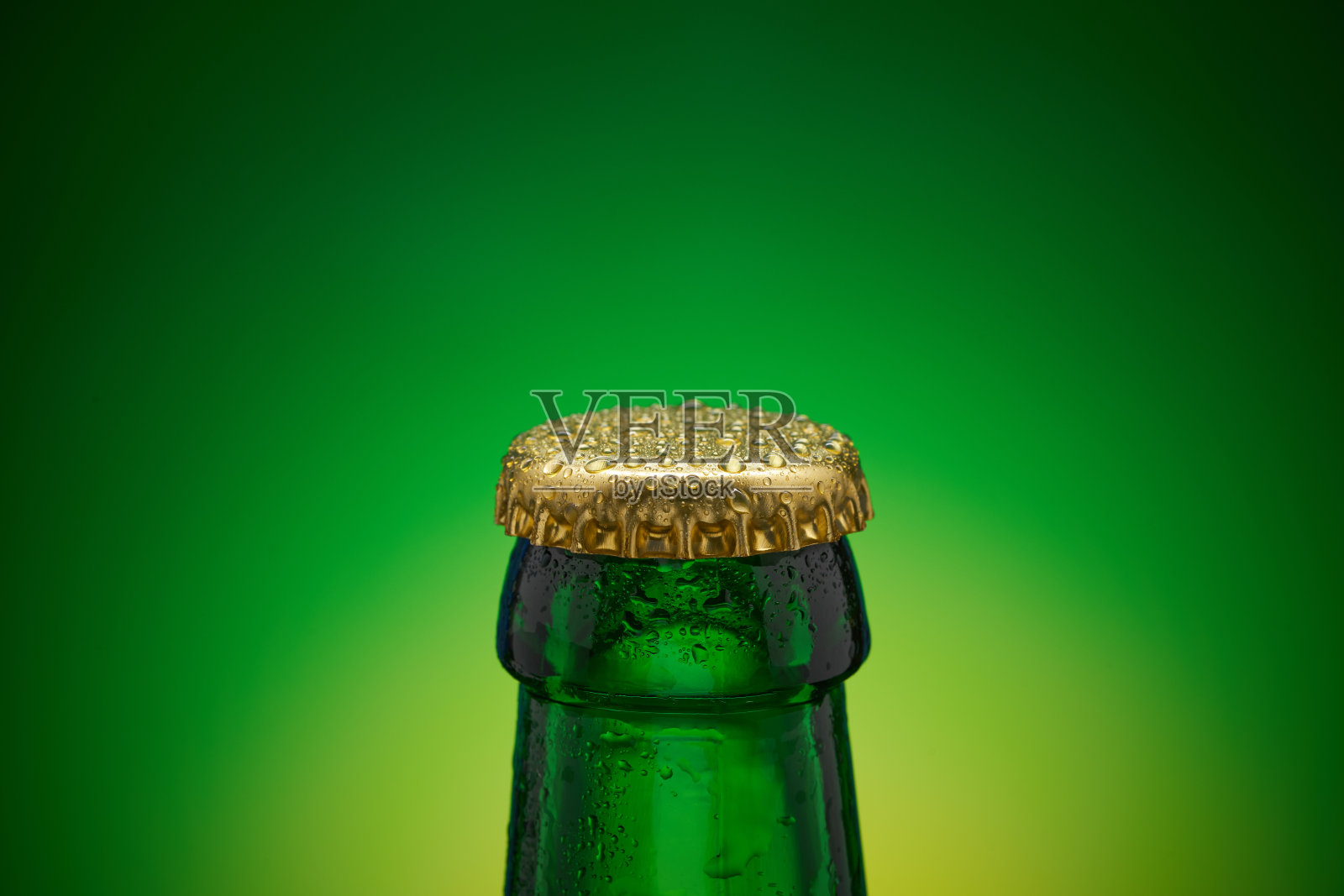 特写的绿色瓶子与金色的盖子和滴在它的黄色绿色背景。库存图片照片摄影图片