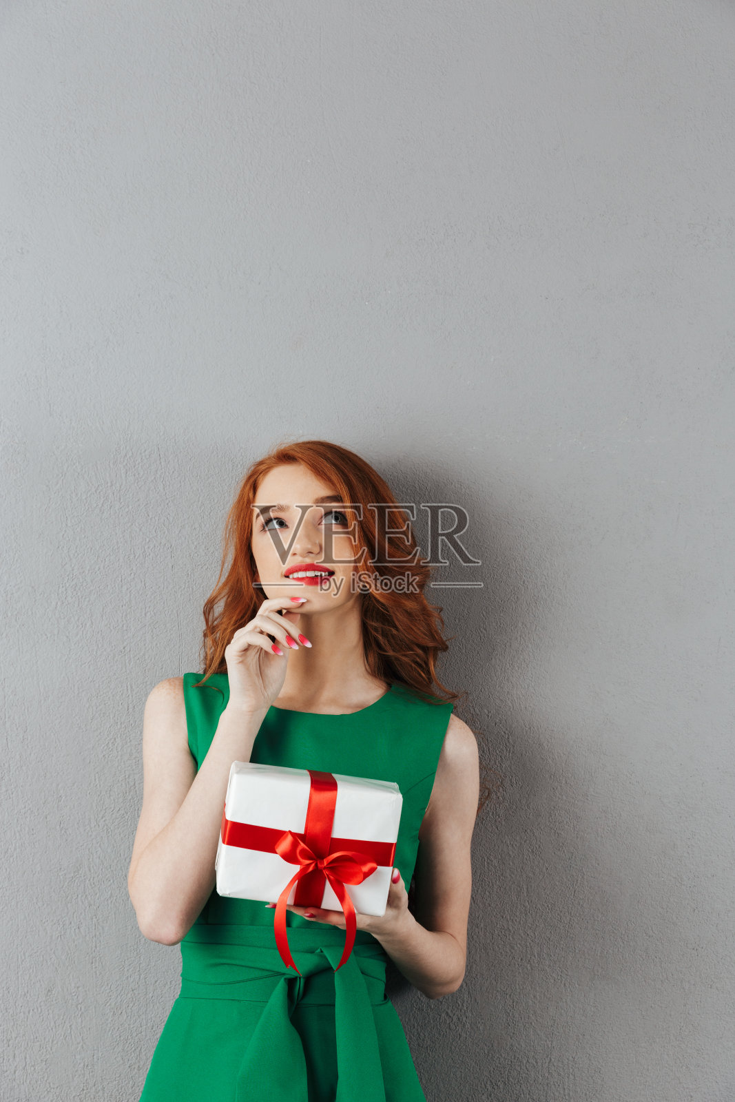 想着穿着绿衣服的红发年轻女子，抱着惊喜照片摄影图片