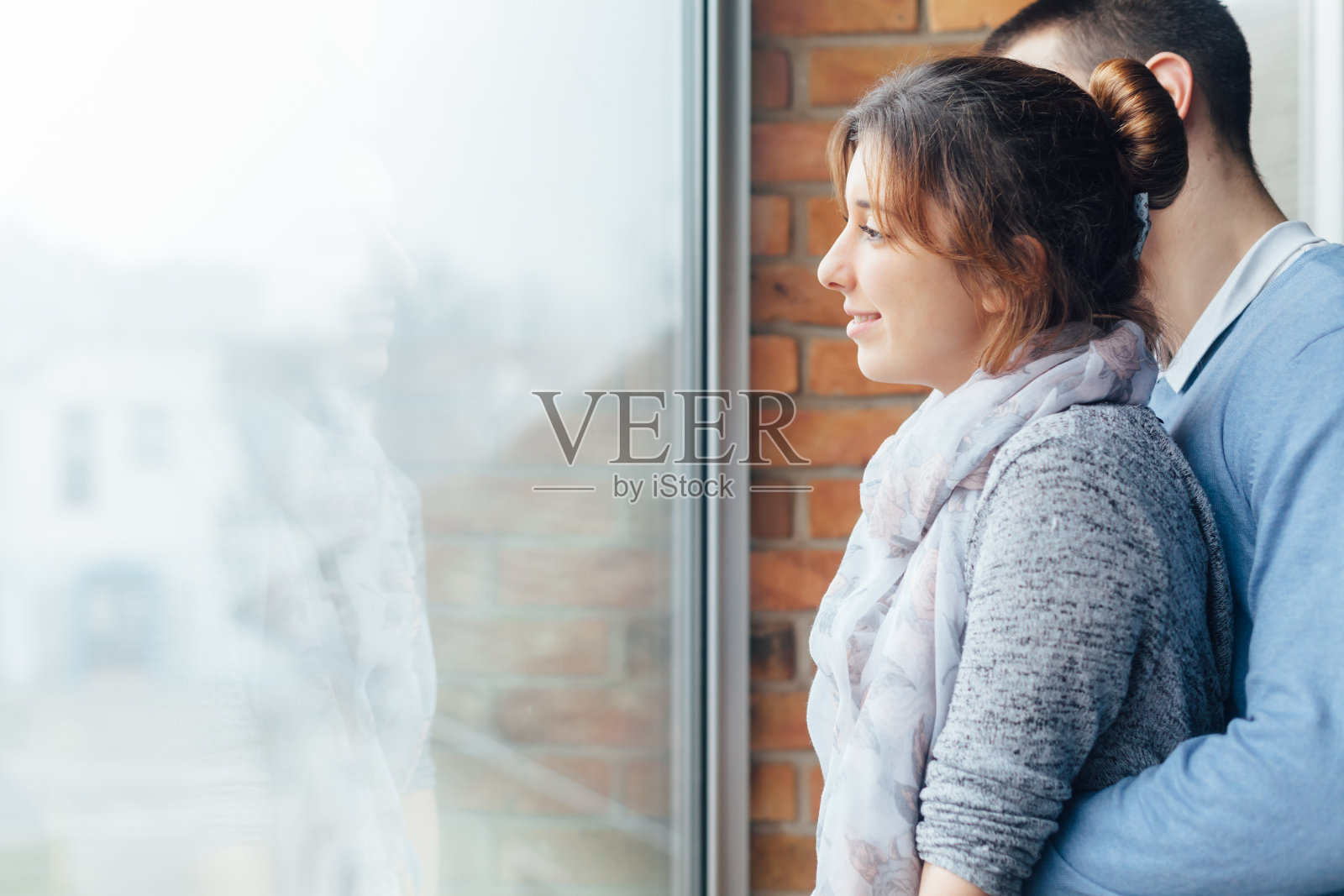 相爱的年轻情侣在窗边紧紧相拥照片摄影图片