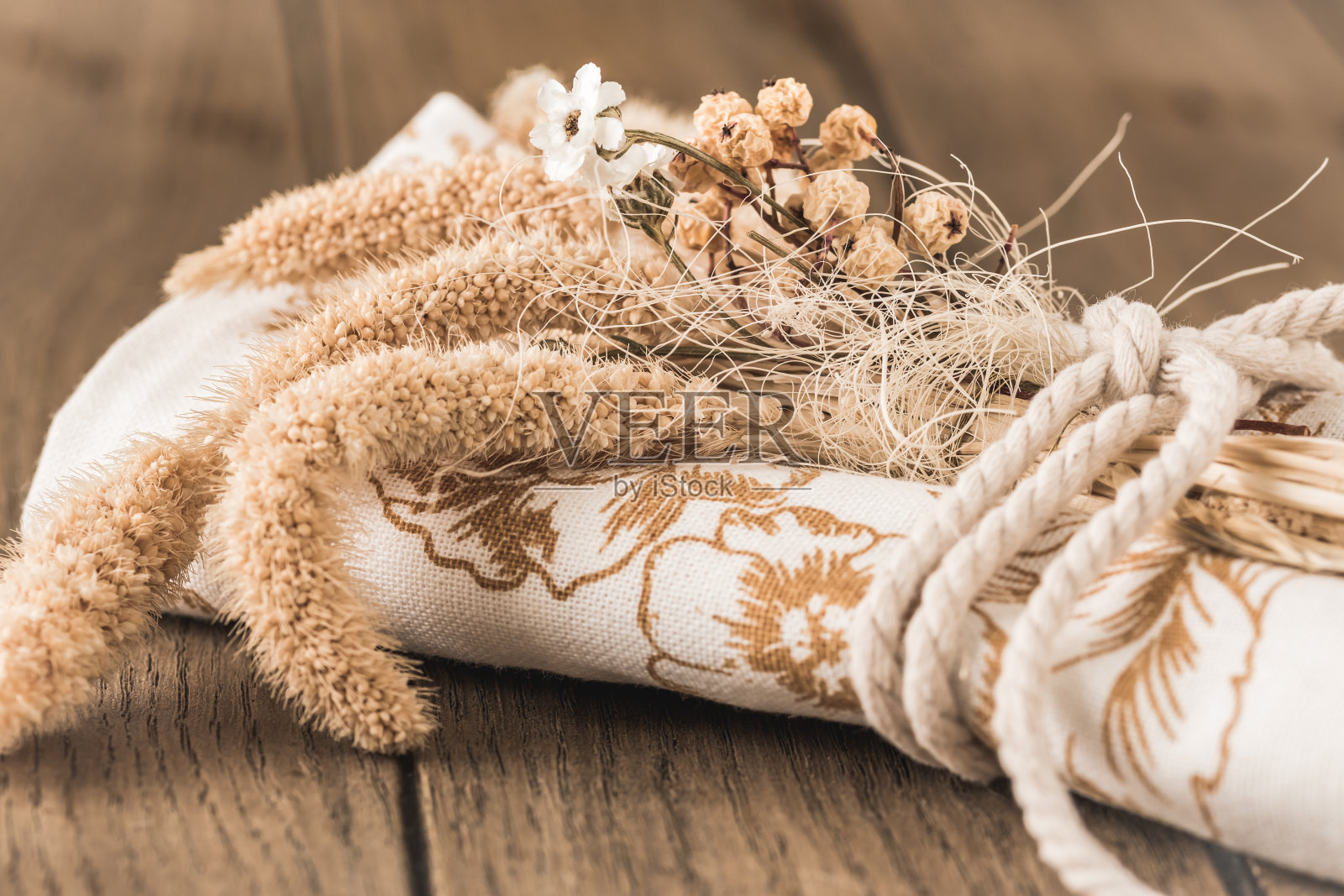 用干花和缎带装饰的卷餐巾或茶巾，以天然颜色放在木桌上作为餐桌装饰照片摄影图片