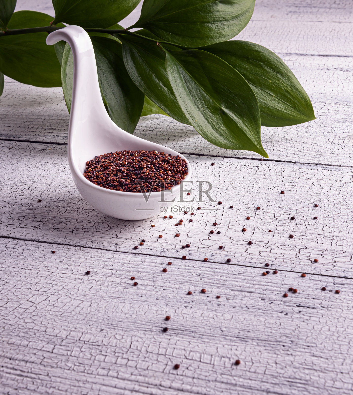 生的红色藜麦种子在勺子碗在白色的桌子上照片摄影图片