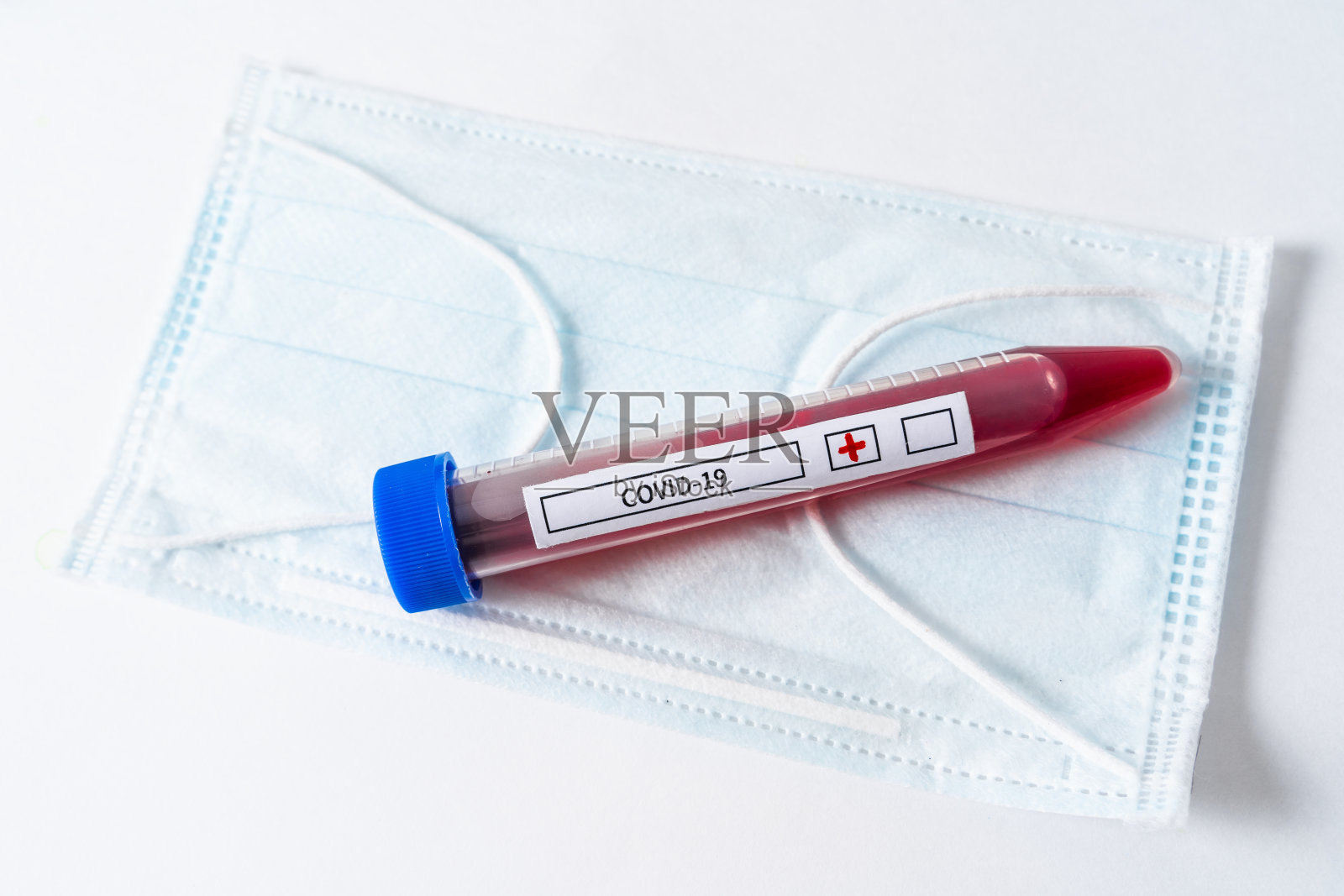 一个带有被病毒感染血液的试管躺在一个面罩上照片摄影图片