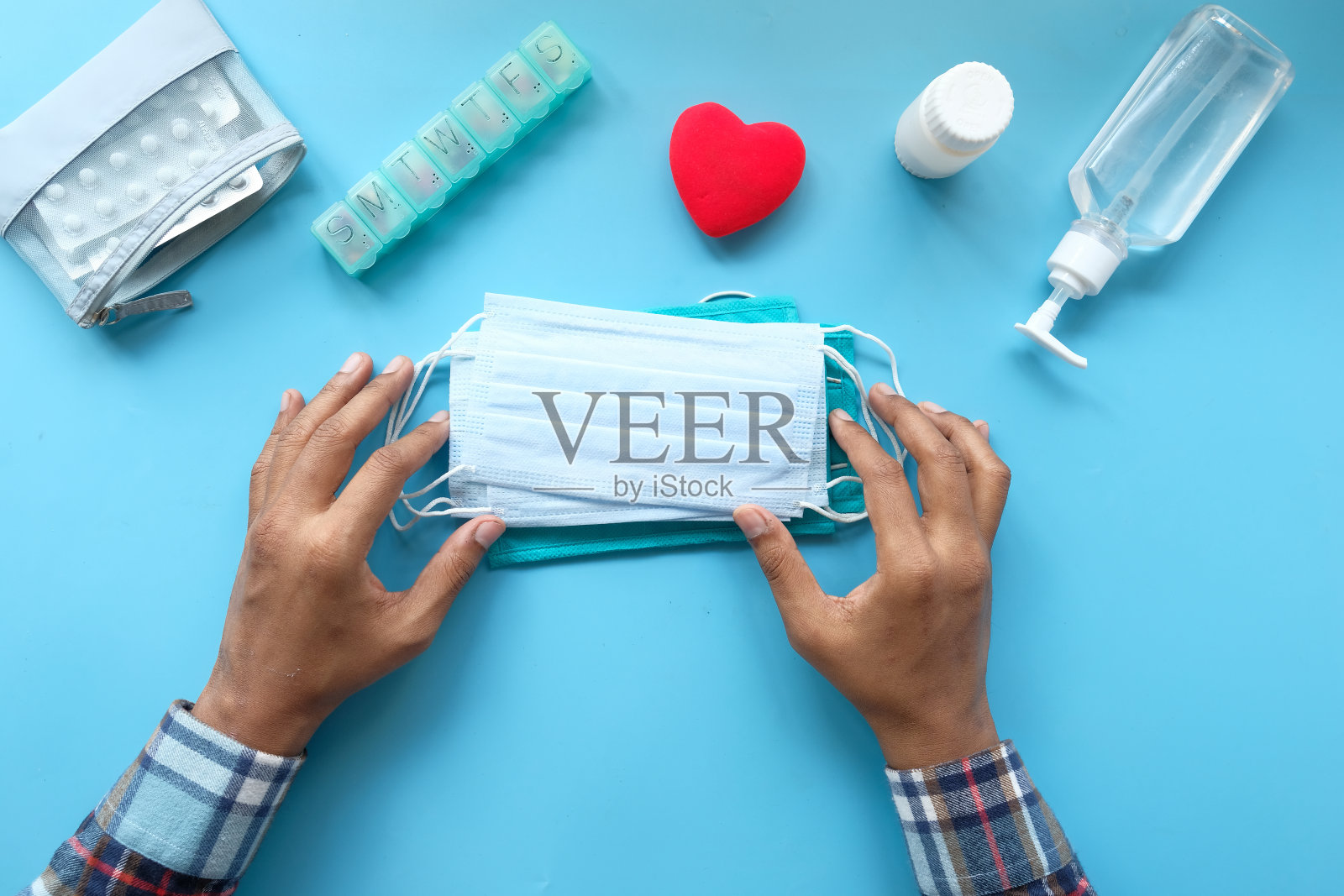 在蓝色背景下，男人的手拿着外科口罩的俯视图照片摄影图片